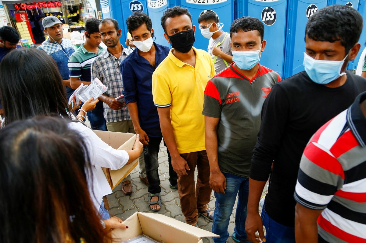 Lidé v Bangladéši stojí ve frontě na ochranné masky a měření teploty.