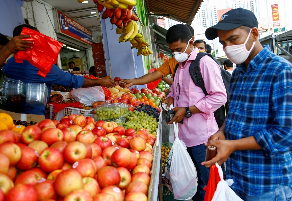 Lidé v Bangladéši nakupují potraviny v ochranných maskách.