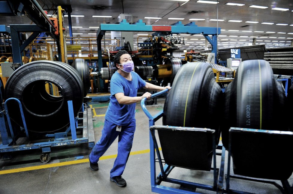 Pracovník výrobny pneumatik v Číně se proti nákaze koronavirem brání rouškou.