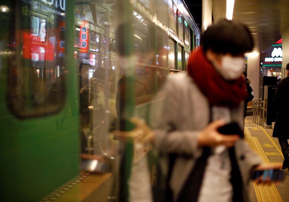 Muž v roušce opouští tramvaj v Hokkaidu v Japonsku.