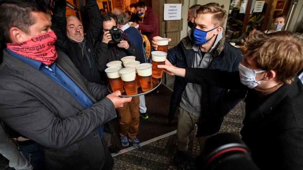 Hosté si berou kelímky s pivem 11. května 2020 v podloubí před restaurací Malostranská beseda v centru Prahy. Po přestávce vynucené šířením nového typu koronaviru hospoda otevřela předzahrádku a nabídla svým návštěvníkům prvních 400 piv zdarma.