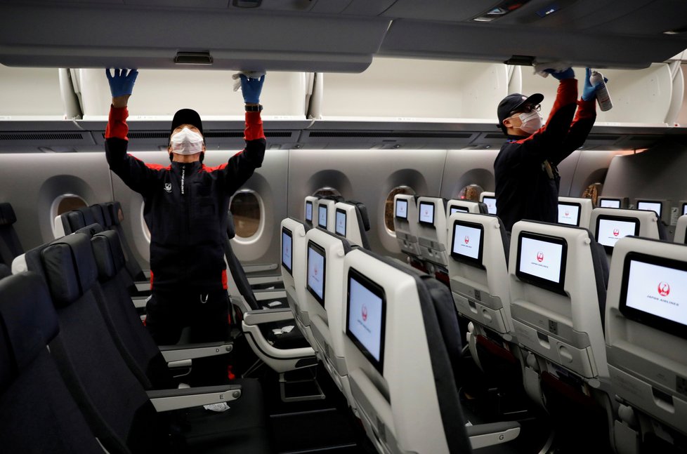 Zaměstnanci aerolinek Japan Airlines po první letu po obnovení vnitrostátní letecké dopravy dezinfikují letadlo, (26.05.2020).