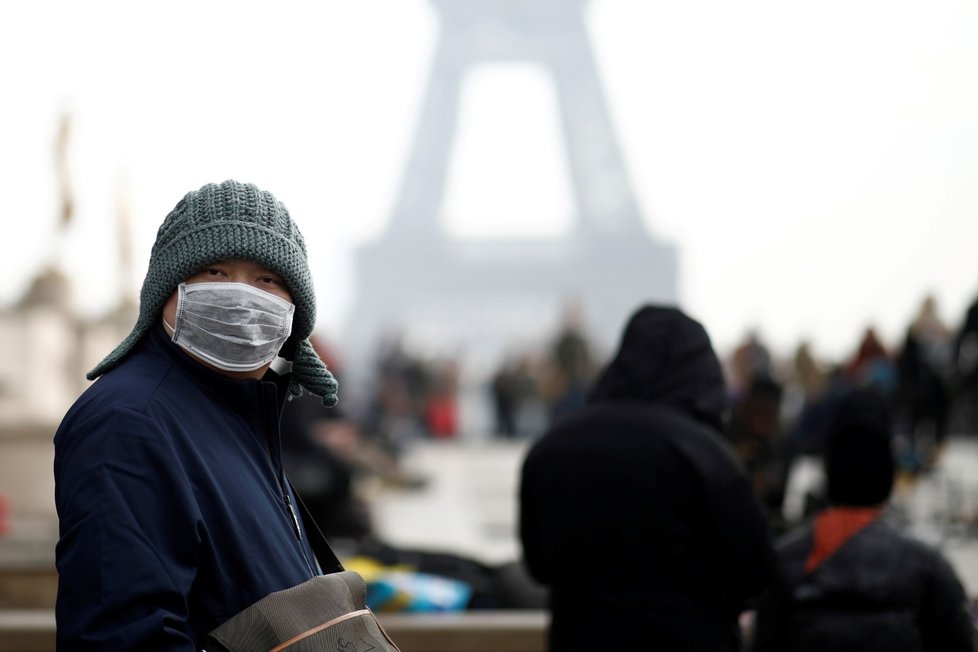 Lidé před Eiffelovou věží se chrání rouškami. Riziko nákazy koronavirem už hrozí i ve Francii (25. 1. 2019)