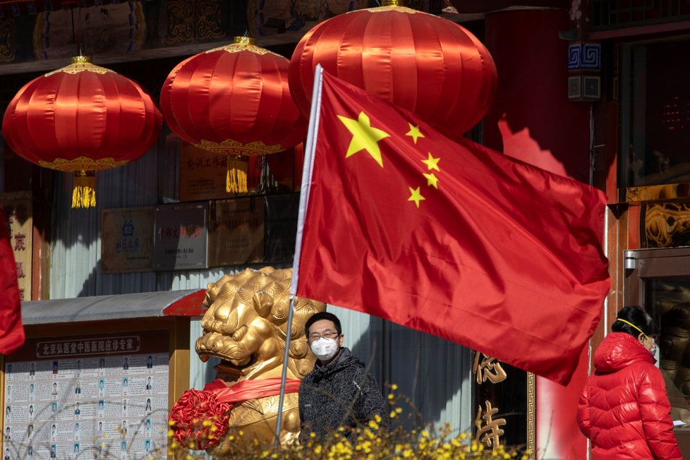 Muž s rouškou u čínské vlajky v Pekingu (3.3.2020)