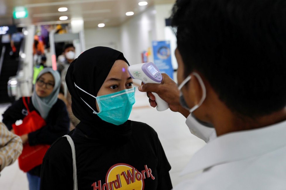 Lékař měří teplotu pasažérům hromadné dopravy v indonéské Jakartě (5.3.2020)