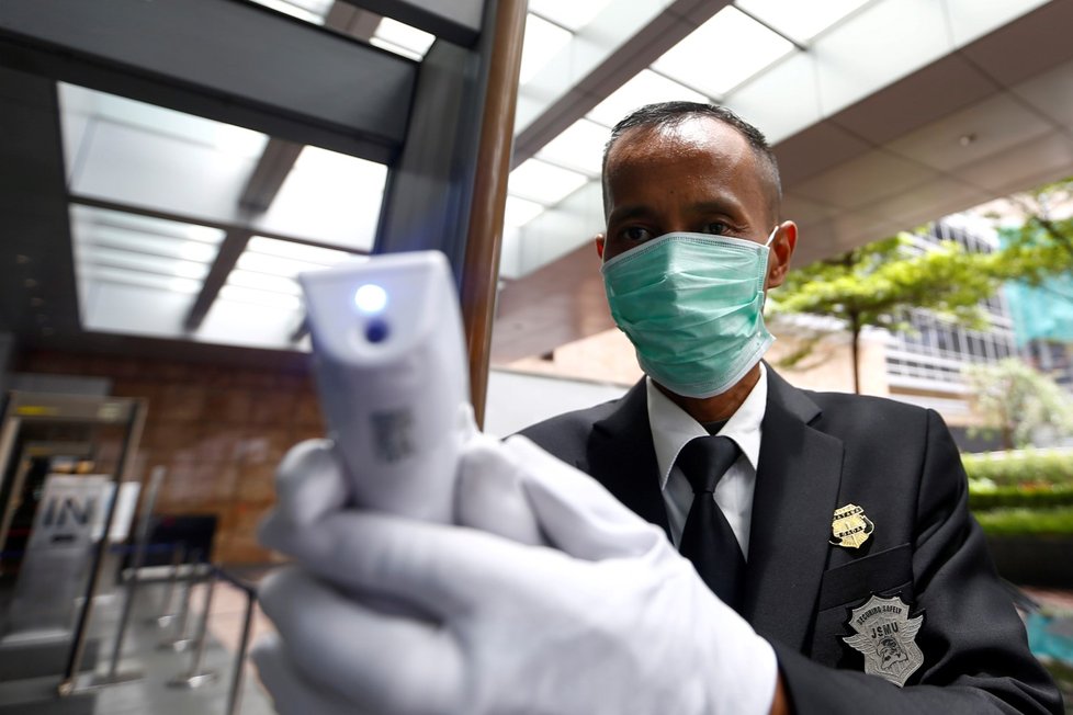 Policista měří teplotu lidem nakupujícím v obchodním domě v indonéské Jakartě (5.3.2020)