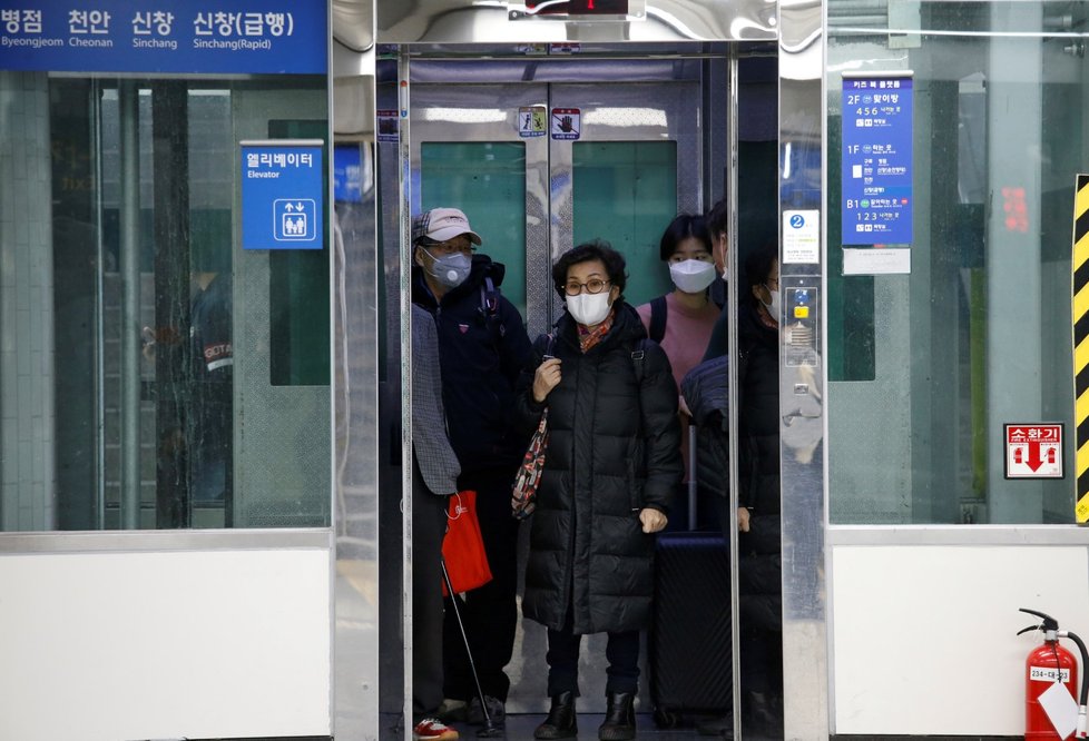Lidé s ochrannými rouškami ve výtahu na stanici metra v Soulu (11.3.2020)