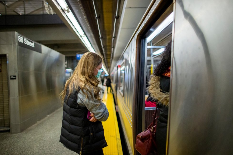 Žena v roušce nastupuje do metra v New York City (4. 3. 2020)