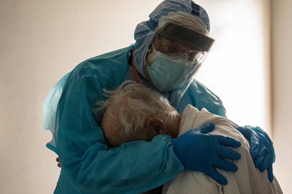 Dojemný snímek lékaře utěšujícího pacienta s koronavirem: Starší lidé izolaci snáší nejhůře.