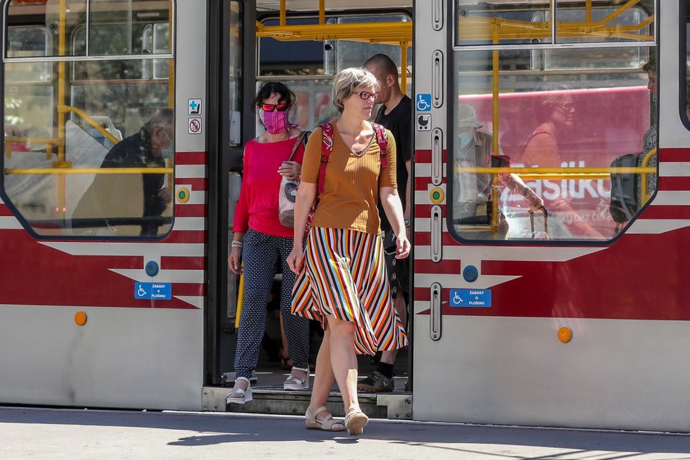 Lidé nosí roušky i v tramvajích.