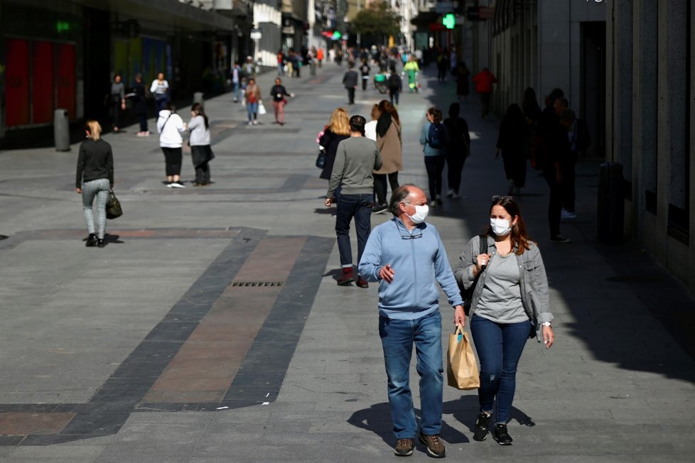 Ulice Madridu jsou neobvykle prázdné, lidé na ulici se chrání rouškami