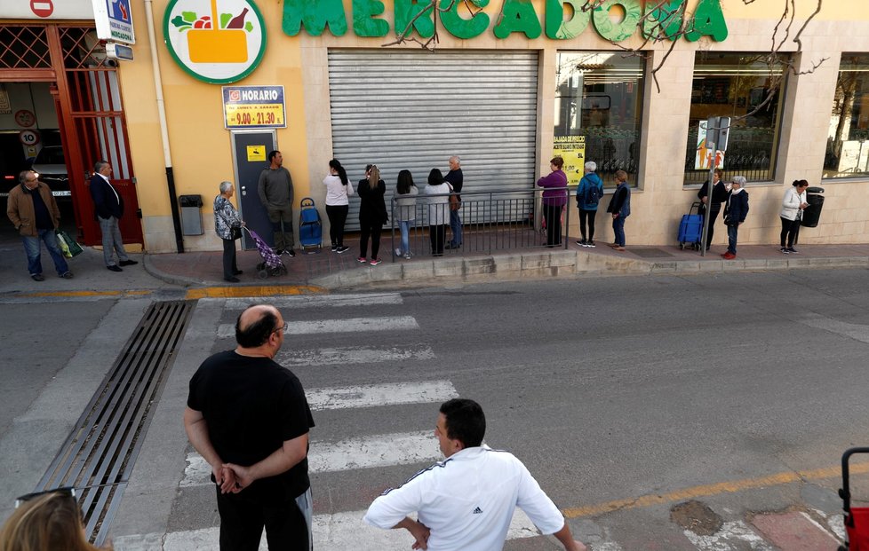 Ve Španělsku se tvoří dlouhé fronty před vstupem do místního supermarketu, lidé nadále skupují potraviny ve velkém