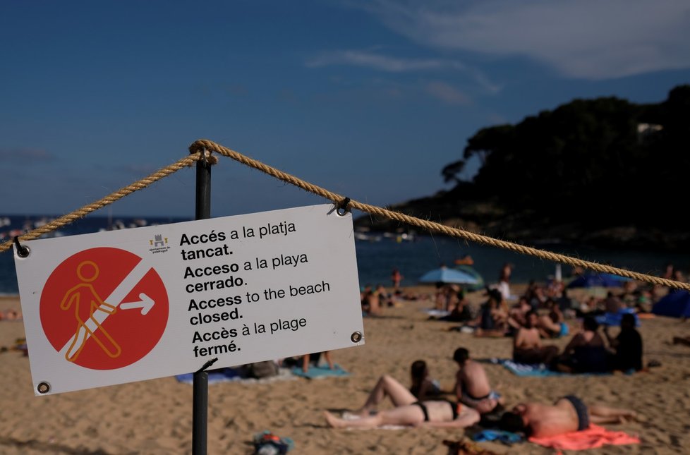 Ačkoliv nápis hlásí, že pláž je zavřená, Španělé si užívají moře (28. 6. 2020).
