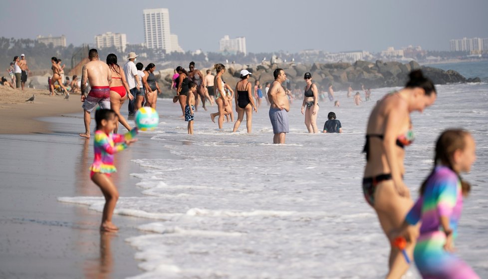 Lidé v Americe si užívají na plážích, někteří nosí roušky.
