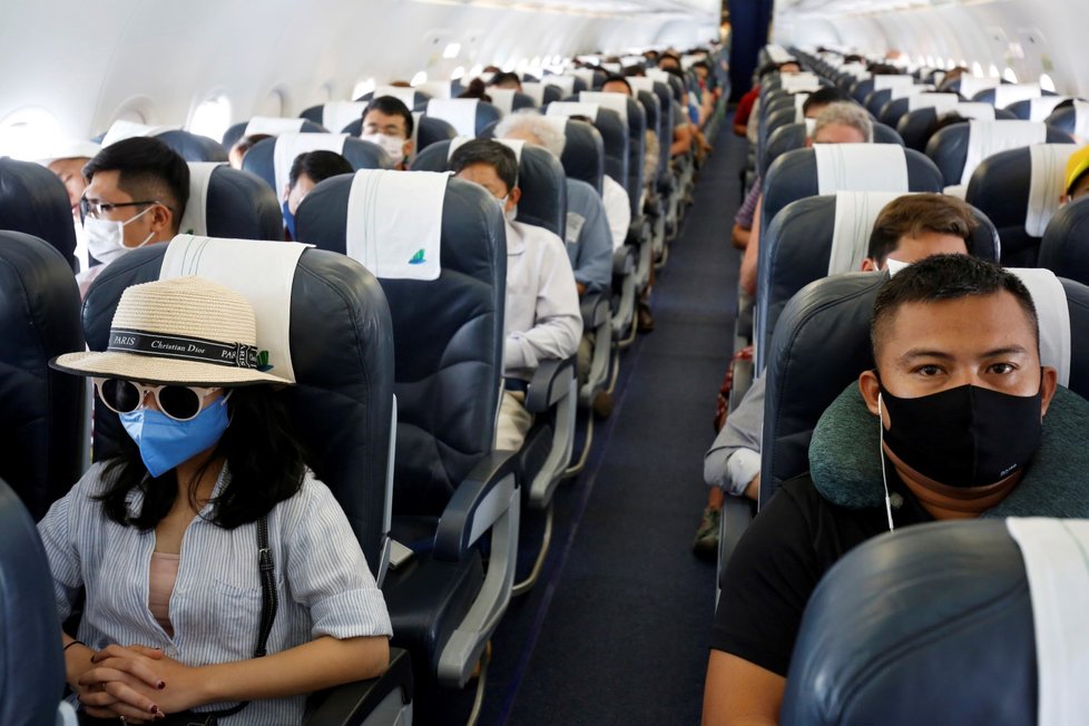 Lidé v rouškách na palubě letadla na cestě do Hanoje