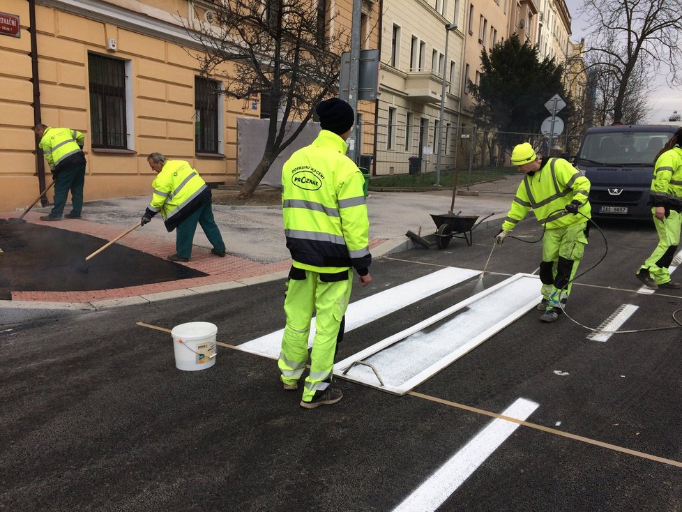 Pracovníci firmy umísťují na novou silnici přechod pro chodce.