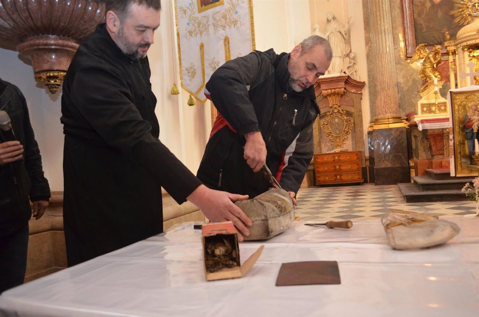 Muzejníci pod dohledem představeného chrámu Sergije Mackuly stříhají olověnou a pozinkovanou schránku, ukrývající 300 let staré relikvie.