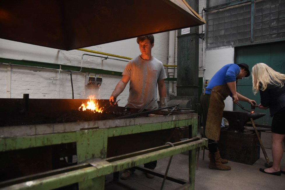 Student Josef Kukučka (22) pracuje s kladivem a u výhně nově zrekonstruované kovárny školy Ave ART v Ostravě. Pedagog Lukáš Dvorský stojí u plastiky slonice. Spirála pro slůně, které teprve na dokončení čeká, stejně jako torzo velblouda v hale.