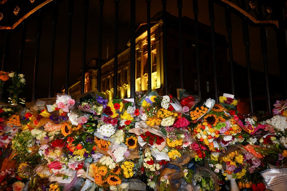 Brány Buckinghamského paláce jsou po smrti královny obsypány květinami truchlících občanů.