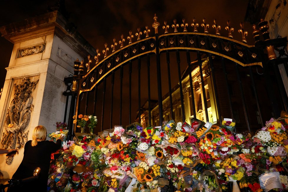 Brány Buckinghamského paláce jsou po smrti královny obsypány květinami truchlících občanů.