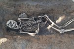 Kostra zavražděné ženy v mělkém hrobě na dně příkopu z 15. století. Hlavu má nepřirozeně zkroucenou do strany.