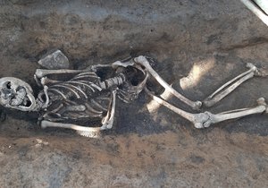 Kostra zavražděné ženy v mělkém hrobě na dně příkopu z 15. století. Hlavu má nepřirozeně zkroucenou do strany.