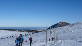 Turisté jdou po cestě mezi Luční boudou a chatou Výrovkou v Krkonoších, vpravo je Sněžka