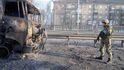 Ukrajinský voják prochází kolem trosek hořícího vojenského náklaďáku na ulici v Kyjevě,