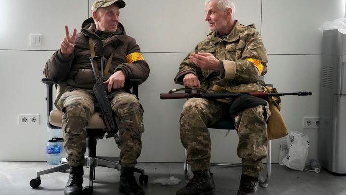 Dva ozbrojení muži civilní obrany spolu mluví na radnici v Kyjevě.