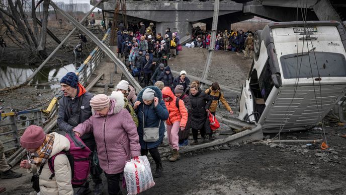 Ukrajinci při útěku z Irpinu procházejí improvizovanou cestu pod zničeným mostem.