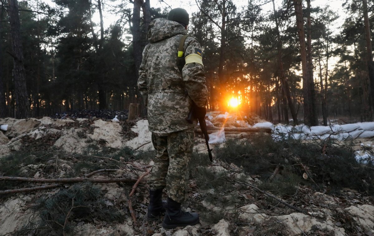 Člen ukrajinských sil územní obrany stojí na stráži, aby bránil město