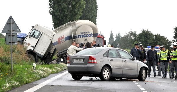 Hasiči na mieste nehody likvidujú únik nafty z prerazenej nádrže nákladného vozu.