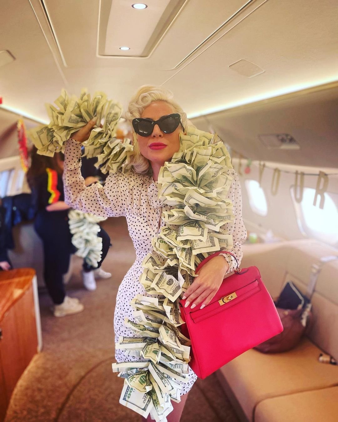 Lady Gaga na palubě soukromého letadla ukázala boa ze stodolarovek.