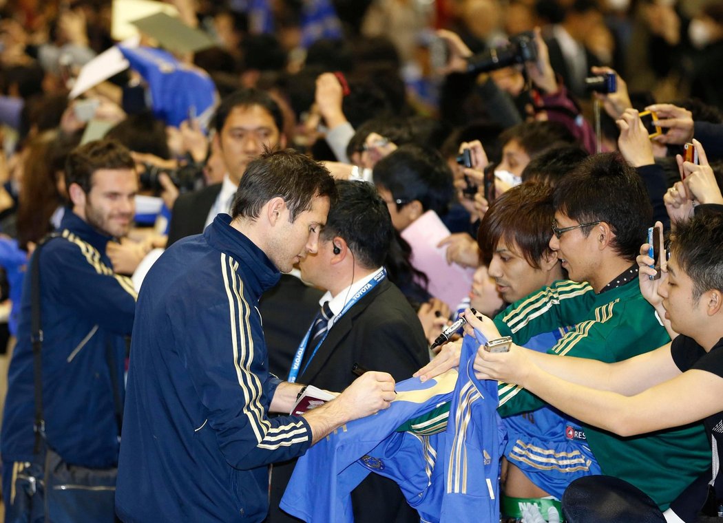 Frank Lampard se podepisuje na repliku   dresu Chelsea, stejně tak Juan Mata v   pozadí.