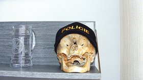 Otřesné! Lidská lebka slouží jako věšák na policejní čepici. Lidské ostatky leží hned vedle skleněného půllitru na pivo. To je neúcta k mrtvému!