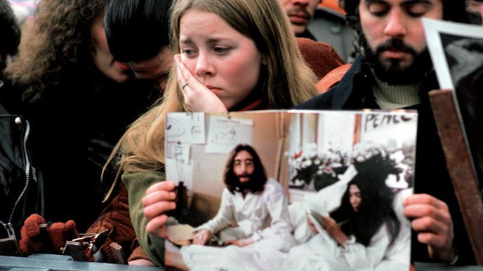 Prosinec 1980. Ve spontánní reakci na Lennonovo zavraždění se v newyorském Central Parku sešly tisíce lidí. Mladý pár drží fotografii Johna Lennona a Yoko Ono během jejich mírového protestu „bed -in“ v Amsterdamu.