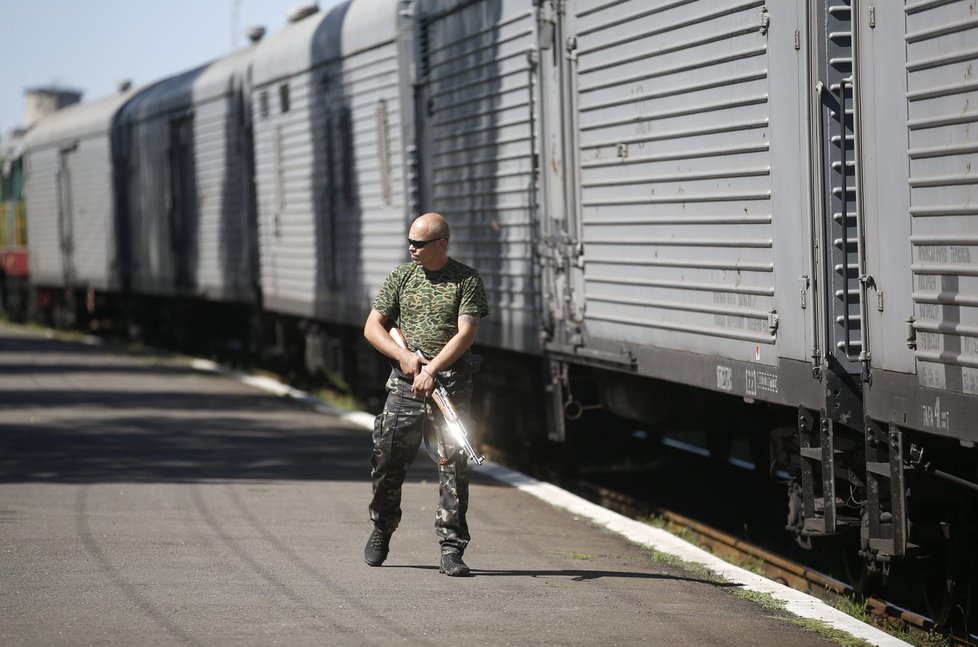 Proruský separatista hlídkuje kolem chladírenských vagónů na nádraží v Torezu