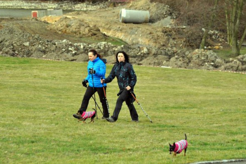 Dvě ženy si klidně s trekingovými holemi a pejsky vyšlapují po pietním území.