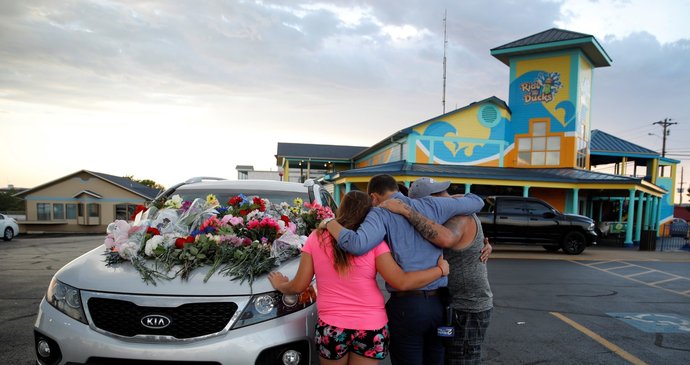 Lidé se modlí u auta, které patřilo jedné z obětí lodního neštěstí.
