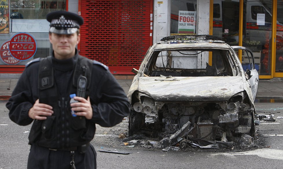 Policista stojí u vraku jednoho ze zapálených vozidel