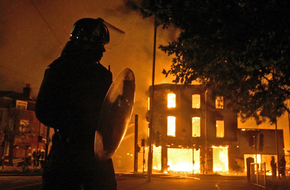 Policista kráčí k další ze zapálených londýnských budov