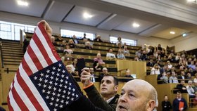 Jeden z Russellových pomocníků začal před Khanem i kamerami mávat americkou vlajkou, tu ale celou dobu držel obráceně.