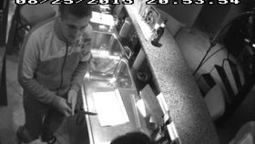 Na tomto záběru z bezpečnostní kamery je vidět lupič s nožem v ruce proti barmance, kterou pak před odchodem z brněnské herny pohladil.