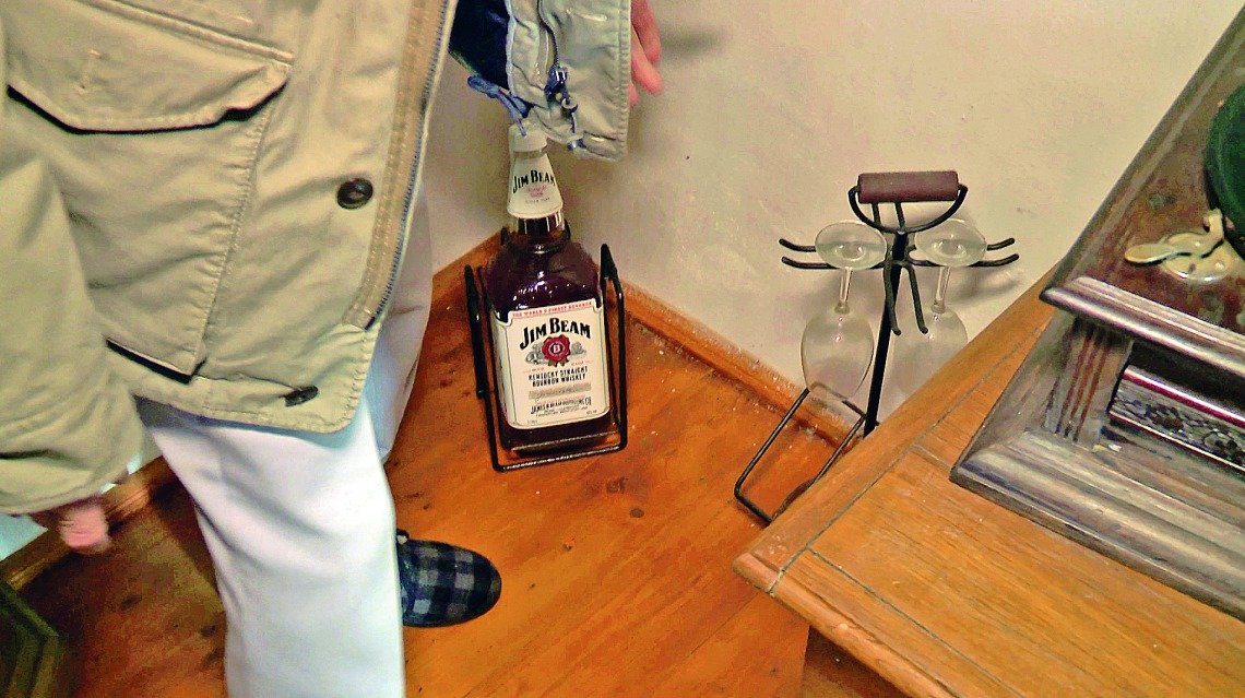 V rohu pokoje stojí dárek od přátel, obří lahev whisky.