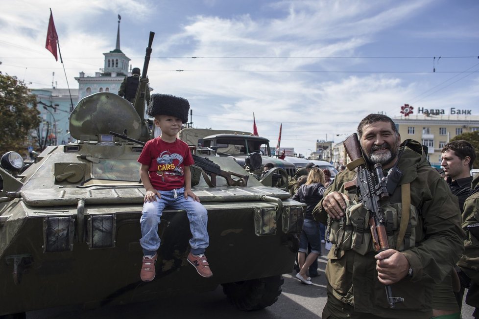 Malý kluk pózuje na obrněnci v Luhansku.