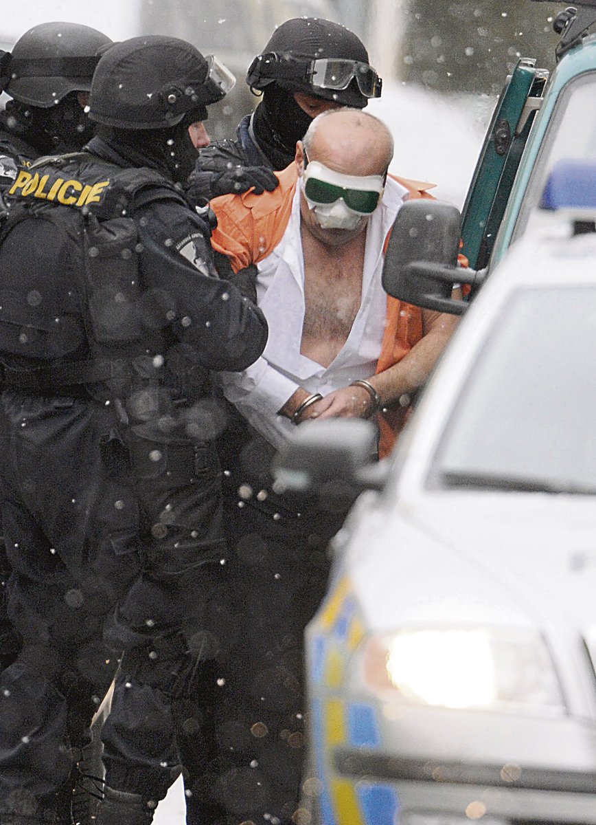 Takhle zná lupiče celé Česko. Zafačovaného a s brýlemi přes oči, jak ho po akčním zadržení nakládají policisté do auta.