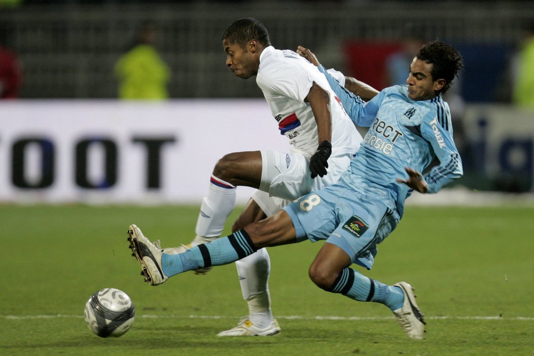 Zadák Marseille se snaží zastavit útočícího hráče Lyonu.