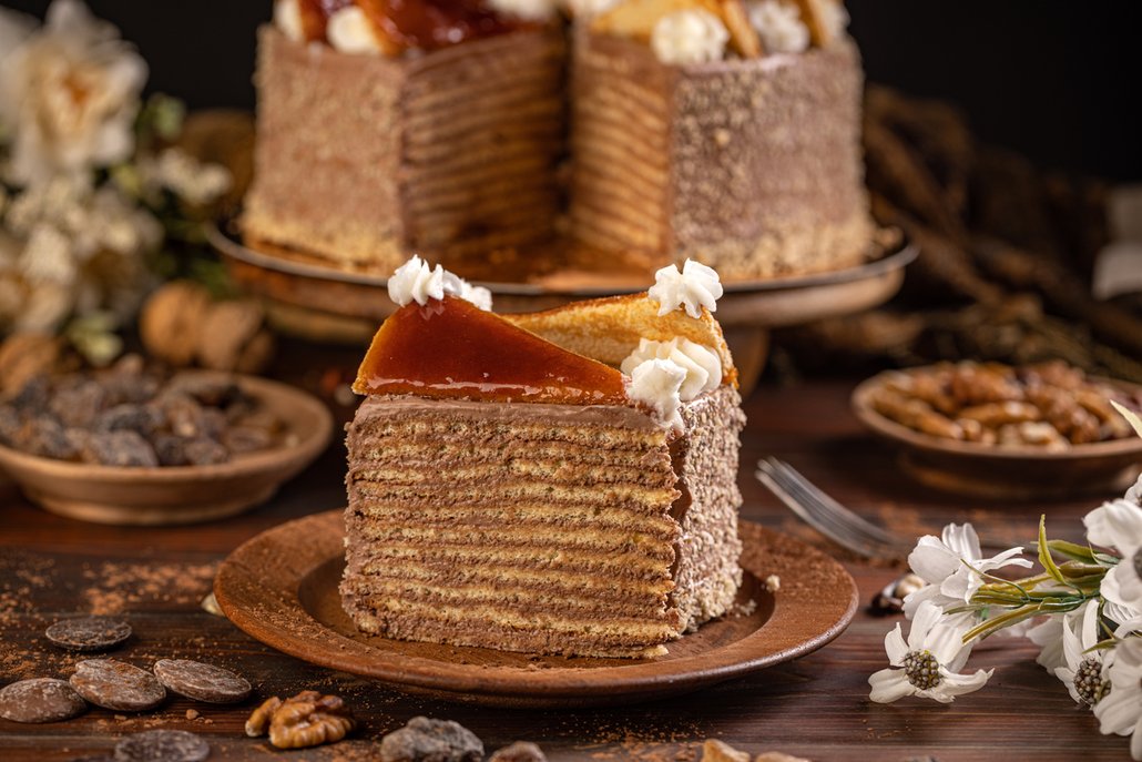 Dobošův dort je originální sedmivrstvý piškotový dort promazaný lahodným máslovým krémem z hořké čokolády doplněný o karamel a zdobený oříšky.