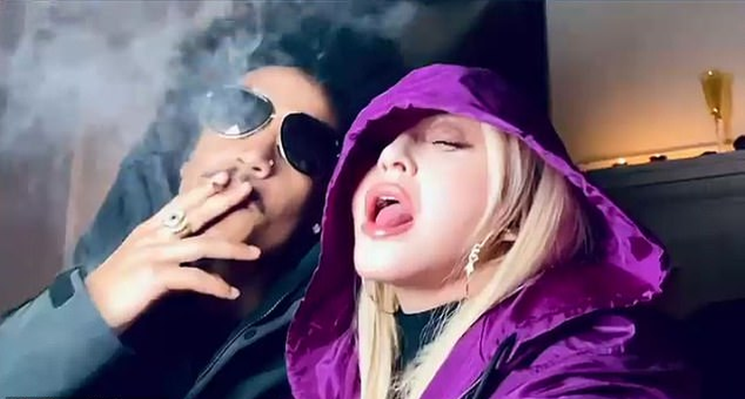 Madonna se dala na trávu. Její fialová kápě včetně originální popisky Purple Reign odkazovala na dalšího milovníka »trávy« Prince (†57)