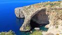 Blue Grotto. Modrá jeskyně je asi nejnavštěvovanější přírodní atrakcí na Maltě. Nachází se na jižním pobřeží. Jedná se vlastně o vysoké skalní útesy, proděravěné na několika místech systémem jeskyní. Atraktivitu místa dotváří hra barev, způsobená zejména v ranních hodinách dopadajícími slunečními paprsky.